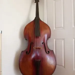 A double bass in front of a white wall and door
